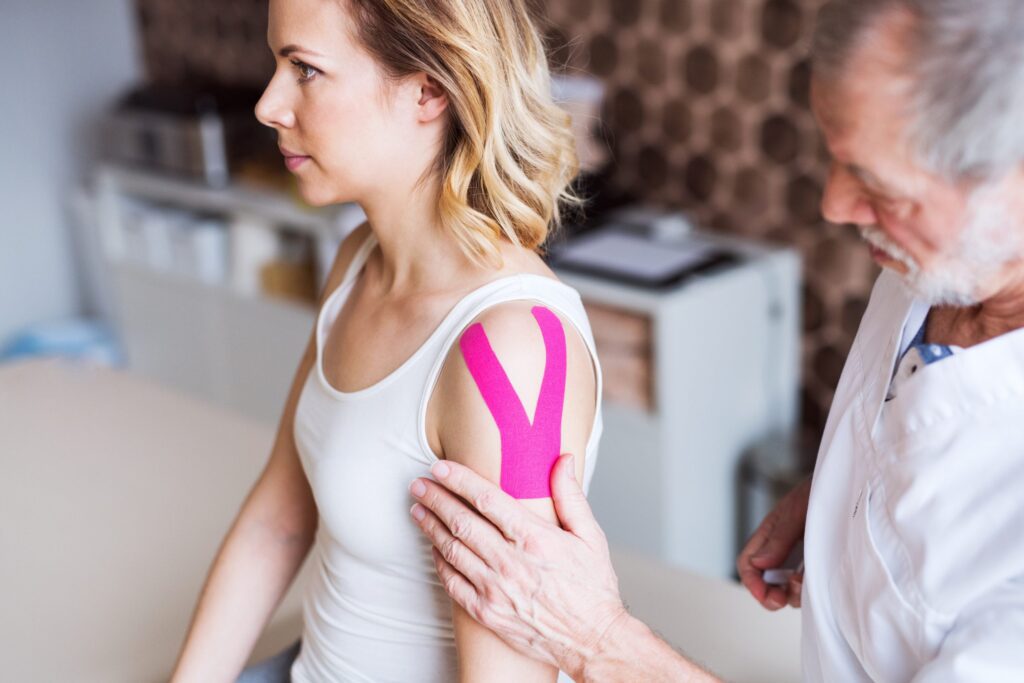 Medical professional applying tape on a patient's shoulder.