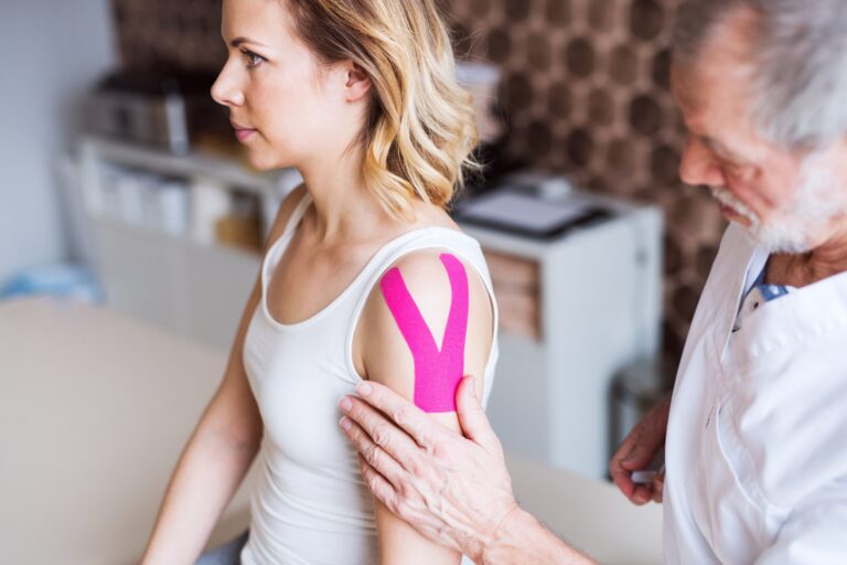 Medical professional applying tape on a patient's shoulder.
