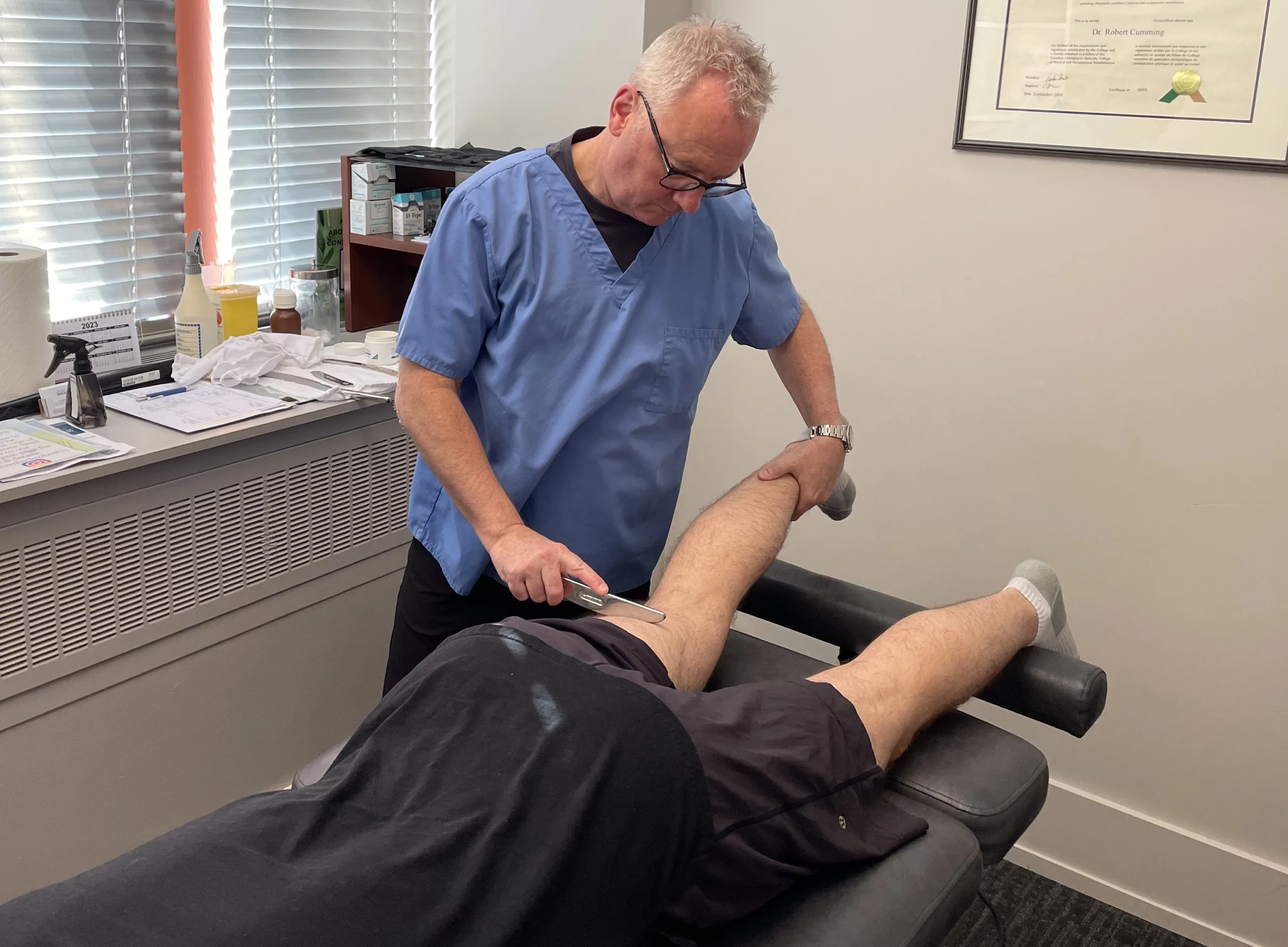 A New Patient is getting his leg massaged in a chiropractor office.