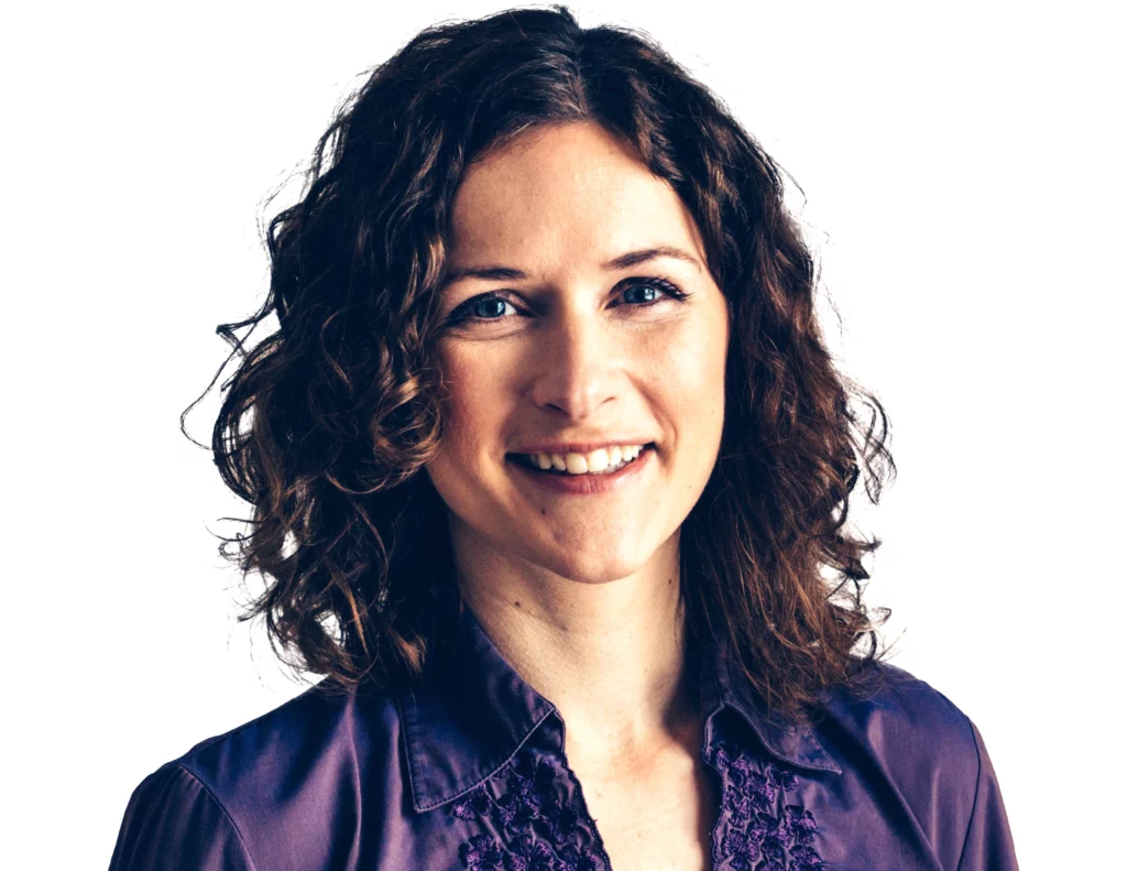 Dr. Jackie Fairbourn with curly hair smiling in a purple shirt.