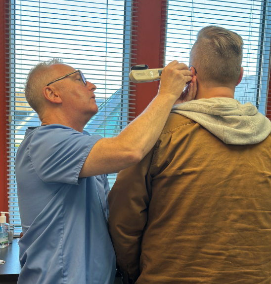 A man receives acupuncture treatment on his ear from a doctor.