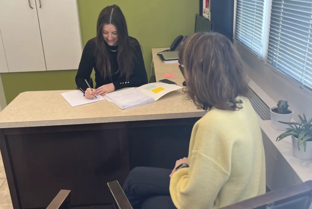 A naturopath sitting at a desk in an office consulting with a patient
