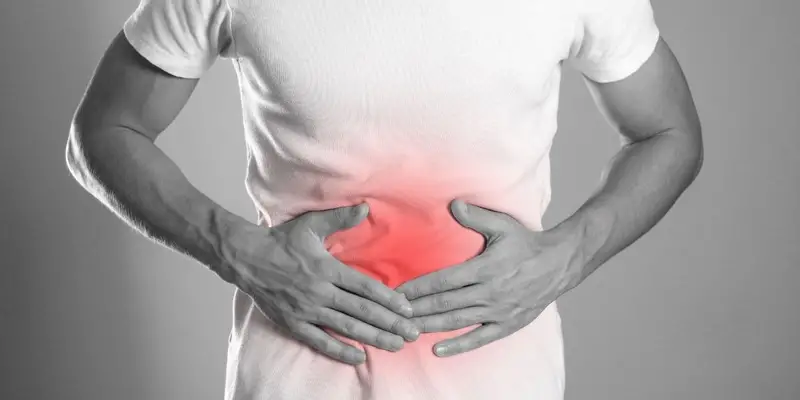 A man holding his stomach with discomfort evident on his face.
