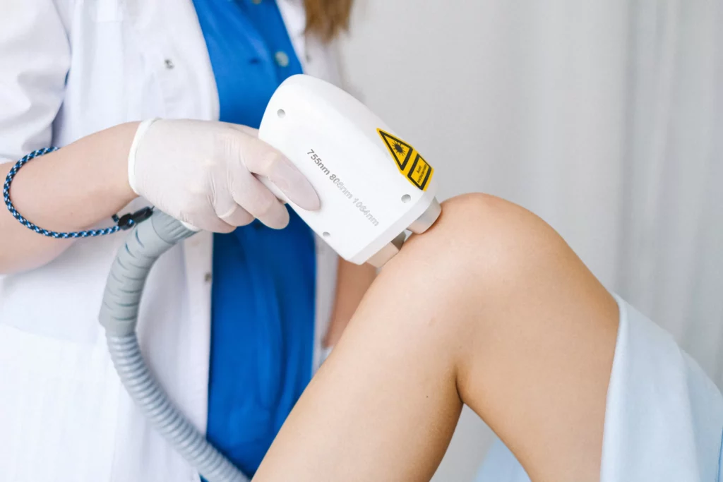 A woman is receiving a laser therapy treatment in a doctor's office.