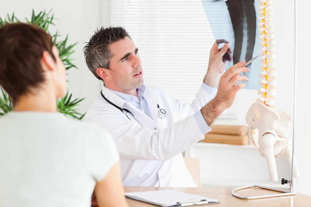 A doctor is analysing an x-ray of a patient's spine to help assess their condition.