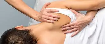 A woman receiving physiotherapy for shoulder pain relief through a soothing back massage.